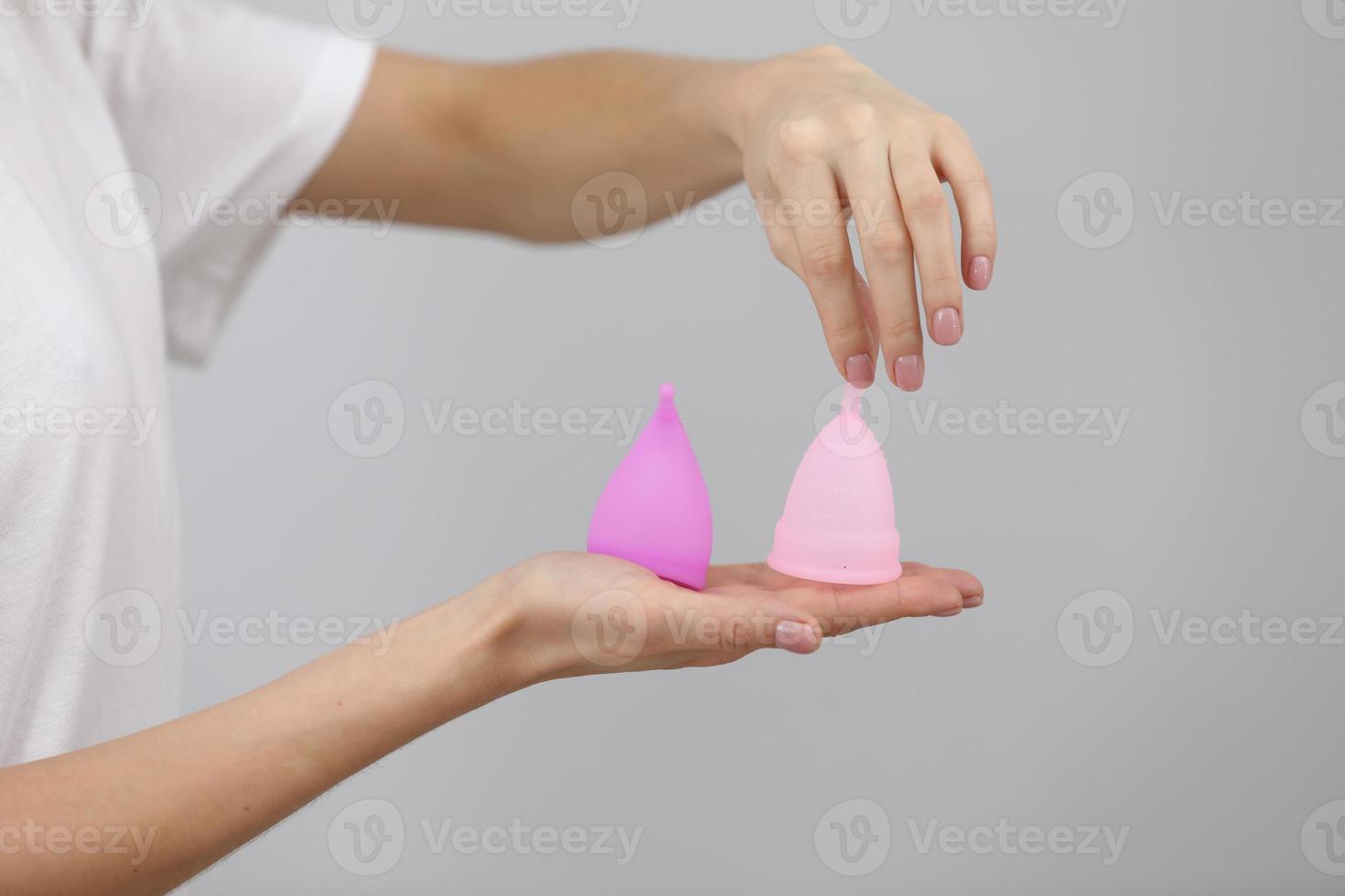 Primo piano di donna che tiene nelle sue mani diversi tipi di coppette mestruali rosa e viola. la scelta della donna. concetto di ginecologia. foto