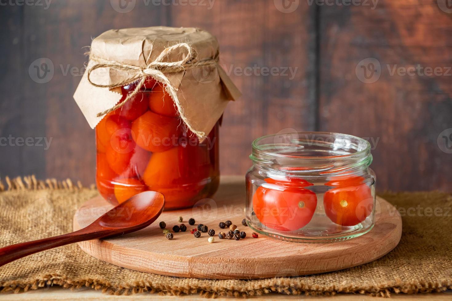 pomodori in salamoia in un barattolo di vetro su fondo in legno foto