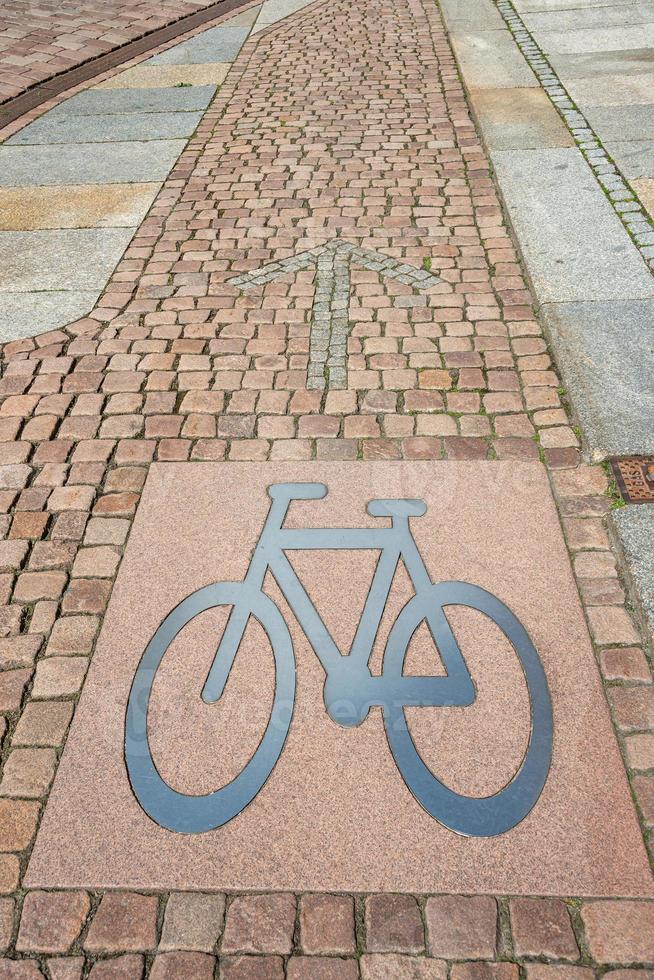 Ciclismo corsia per biciclette fatto nel un vecchio pietra marciapiede strada con un' metallo cartello di bicicletta a il sentiero e un' pietroso freccia puntamento direzione per Ciclismo nel un vecchio Tedesco città. foto