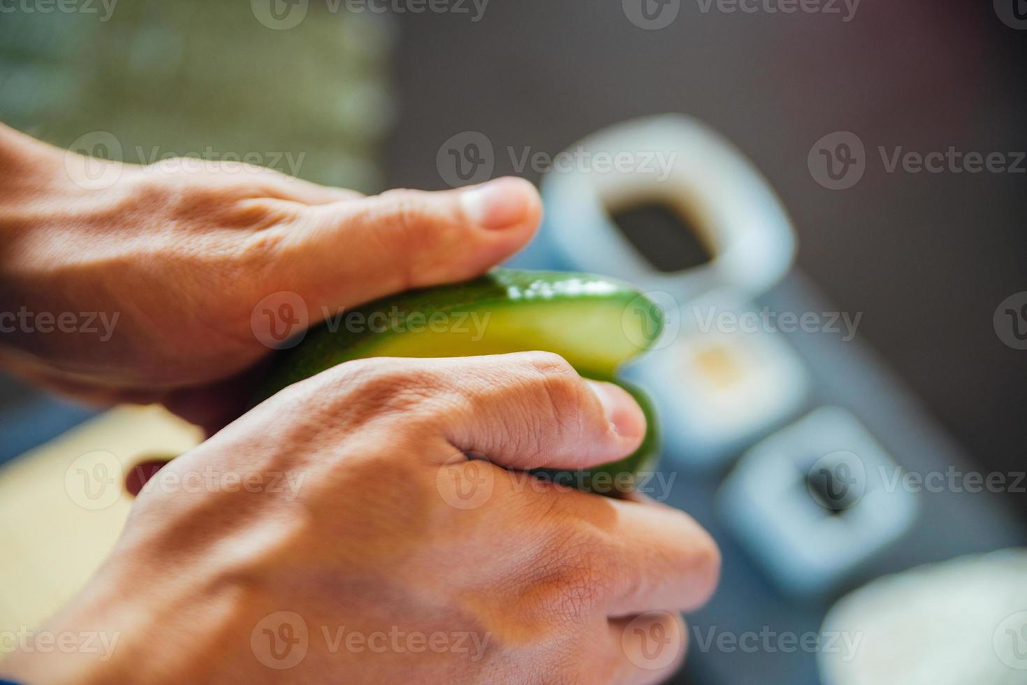 persona che taglia a metà un avocado foto