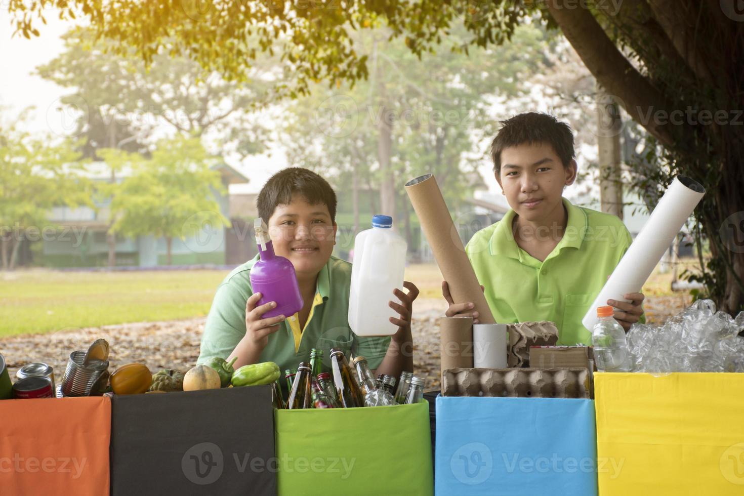 giovane asiatico ragazzo ordinamento vario spazzatura e mettendo loro in il scatole di fronte di lui nel il parco, natura cura e ambiente amore concetto. foto