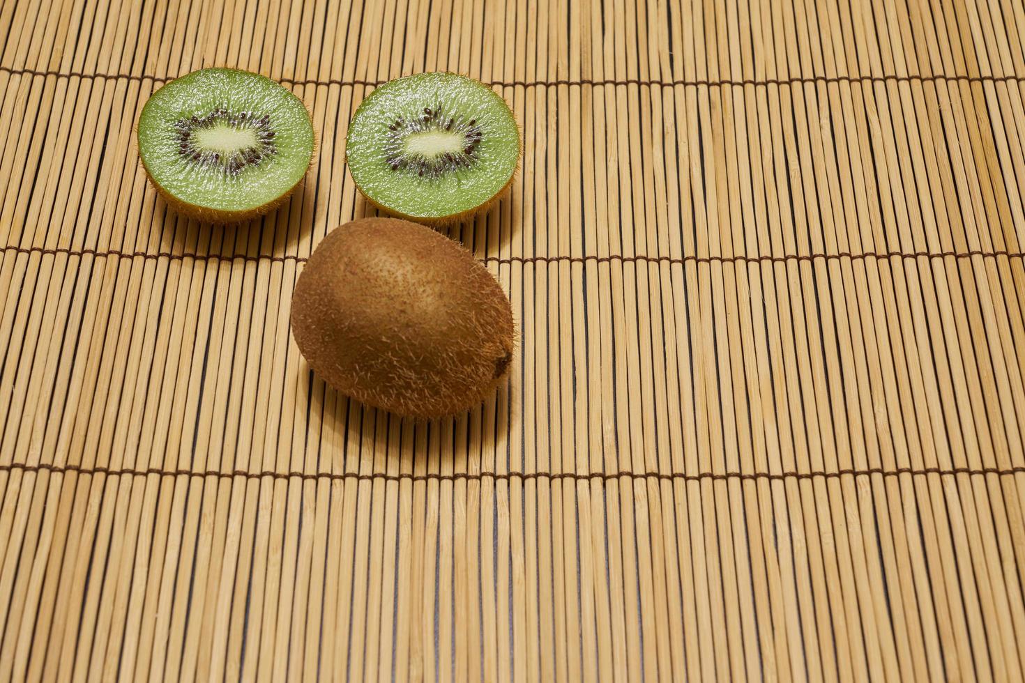 kiwi marrone maturo con kiwi verde tagliato su uno sfondo di paglia con spazio per il testo. foto