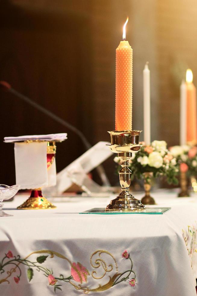 decorazione su il nozze tavolo con candela, rosa vaso, libro, penna nel cristiano matrimonio. nozze cerimonia nel cristiano Chiesa foto