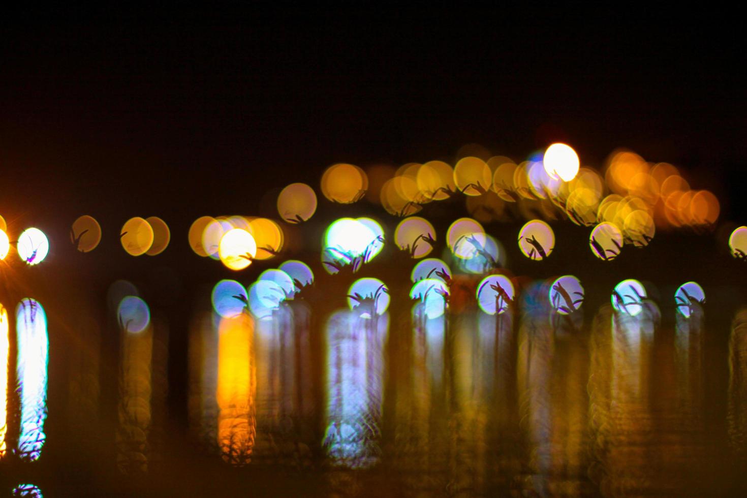 bellissimo notte leggero con bokeh sfocato su fiume e riflesso nel acqua colorato celebrare sfondo foto