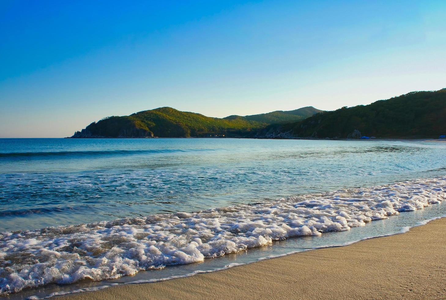 onde sulla spiaggia e le montagne sullo sfondo del mare del giappone foto