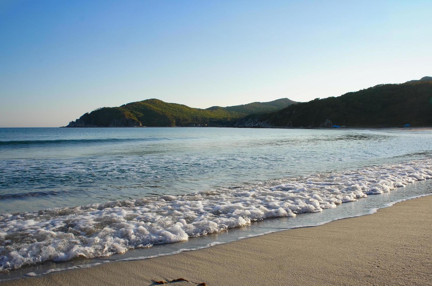 onde sulla spiaggia e le montagne sullo sfondo del mare del giappone foto