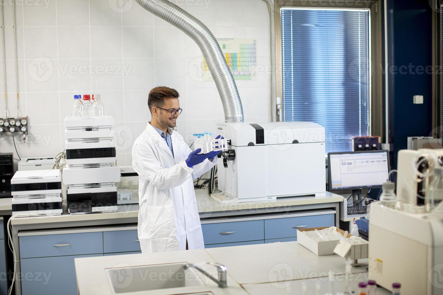 giovane ricercatore che lavora con campioni chimici in laboratorio con sistema hplc e apparecchiature cromatografiche foto