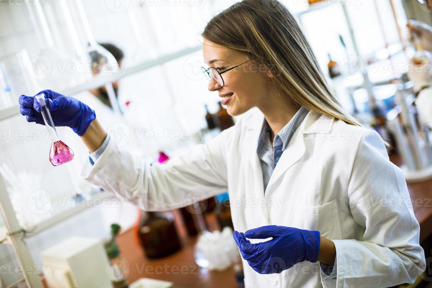 giovane scienziato femminile esaminando liquido nel laboratorio biochimico foto