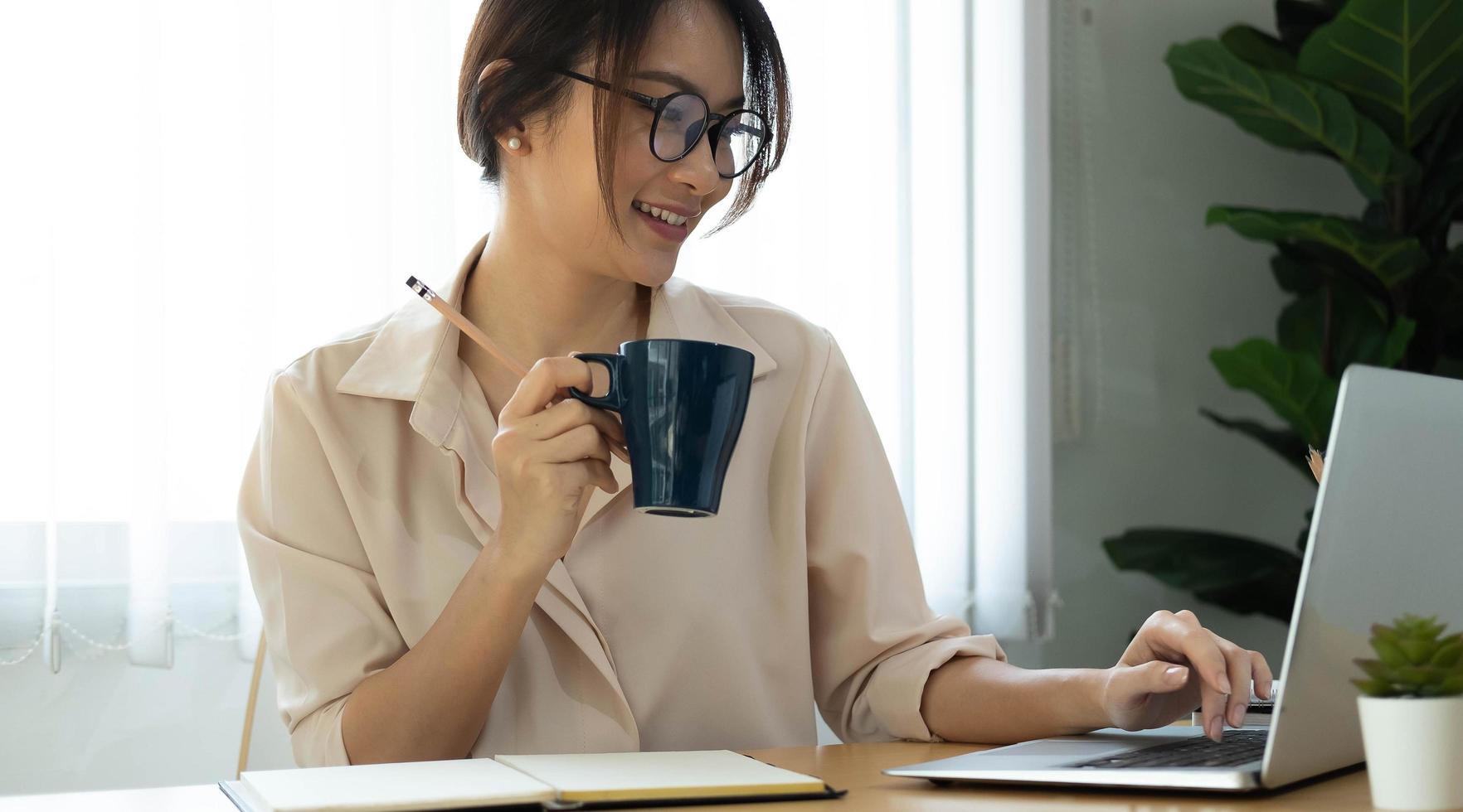 donna che tiene la tazza di caffè mentre si lavora foto