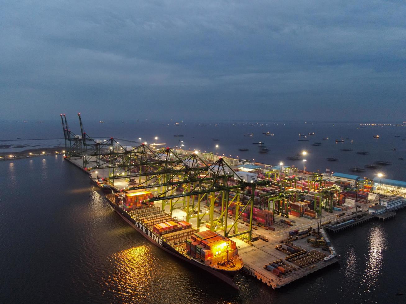 Jakarta, Indonesia 2021- veduta aerea del carico e scarico di navi portacontainer nel porto di acque profonde, importazione logistica ed esportazione di trasporto merci tramite nave portacontainer in mare aperto di notte foto