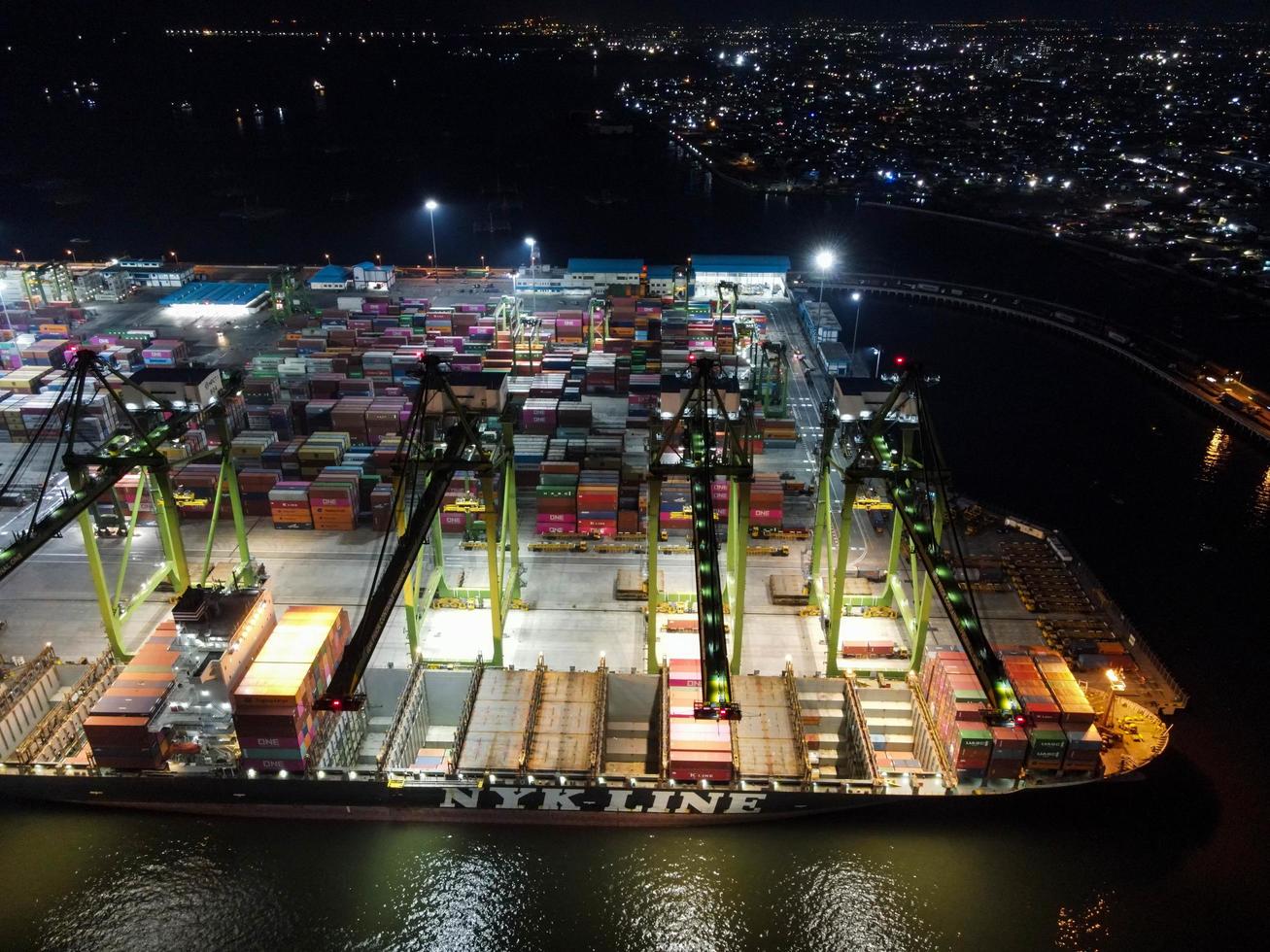 Jakarta, Indonesia 2021- veduta aerea del carico e scarico di navi portacontainer nel porto di acque profonde, importazione logistica ed esportazione di trasporto merci tramite nave portacontainer in mare aperto di notte foto
