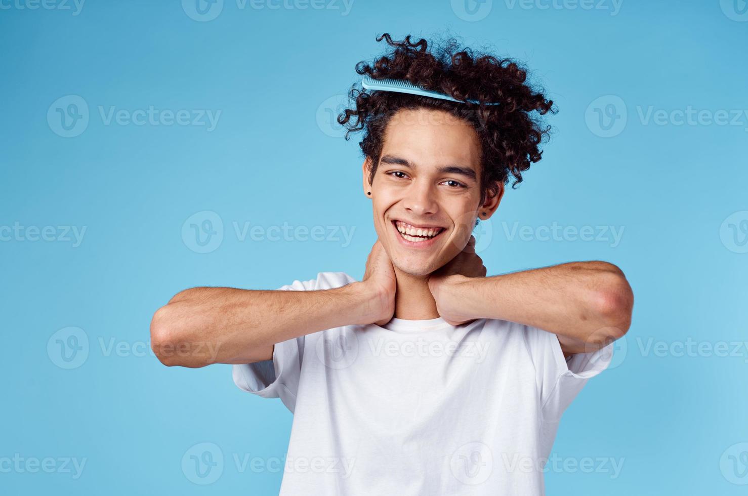 un' uomo con un' pettine nel il suo capelli Esprimere a gesti con il suo mani su un' blu sfondo copia spazio foto