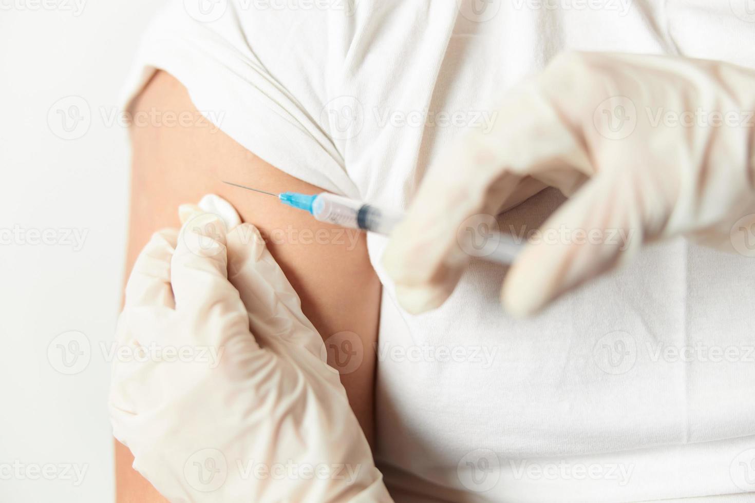 un' medico con guanti iniettare in il spalla avvicinamento covid vaccinazione foto