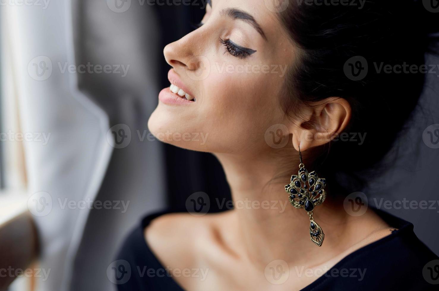 brunetta vicino finestra in posa attraente Guarda orecchini elegante stile foto