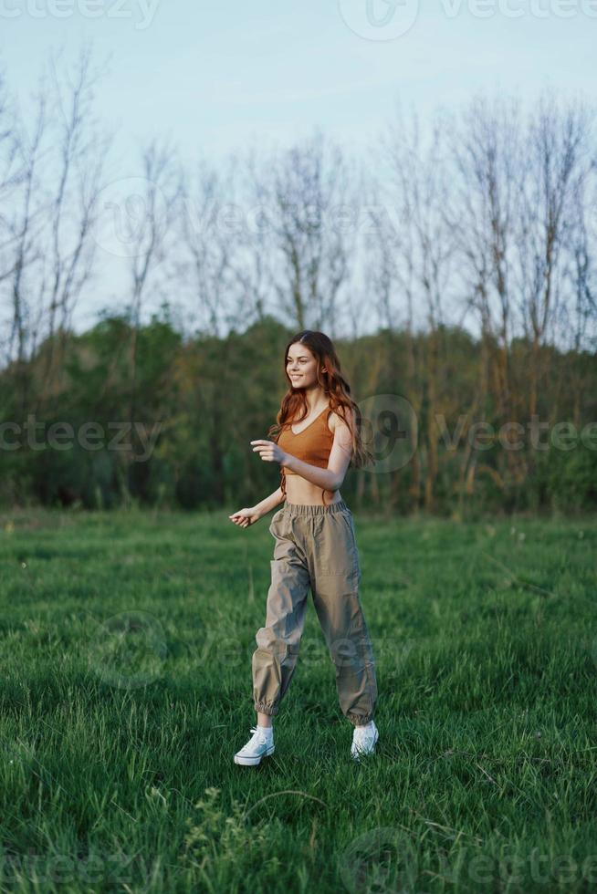 un' donna corre nel il parco su verde erba a un' allenarsi foto