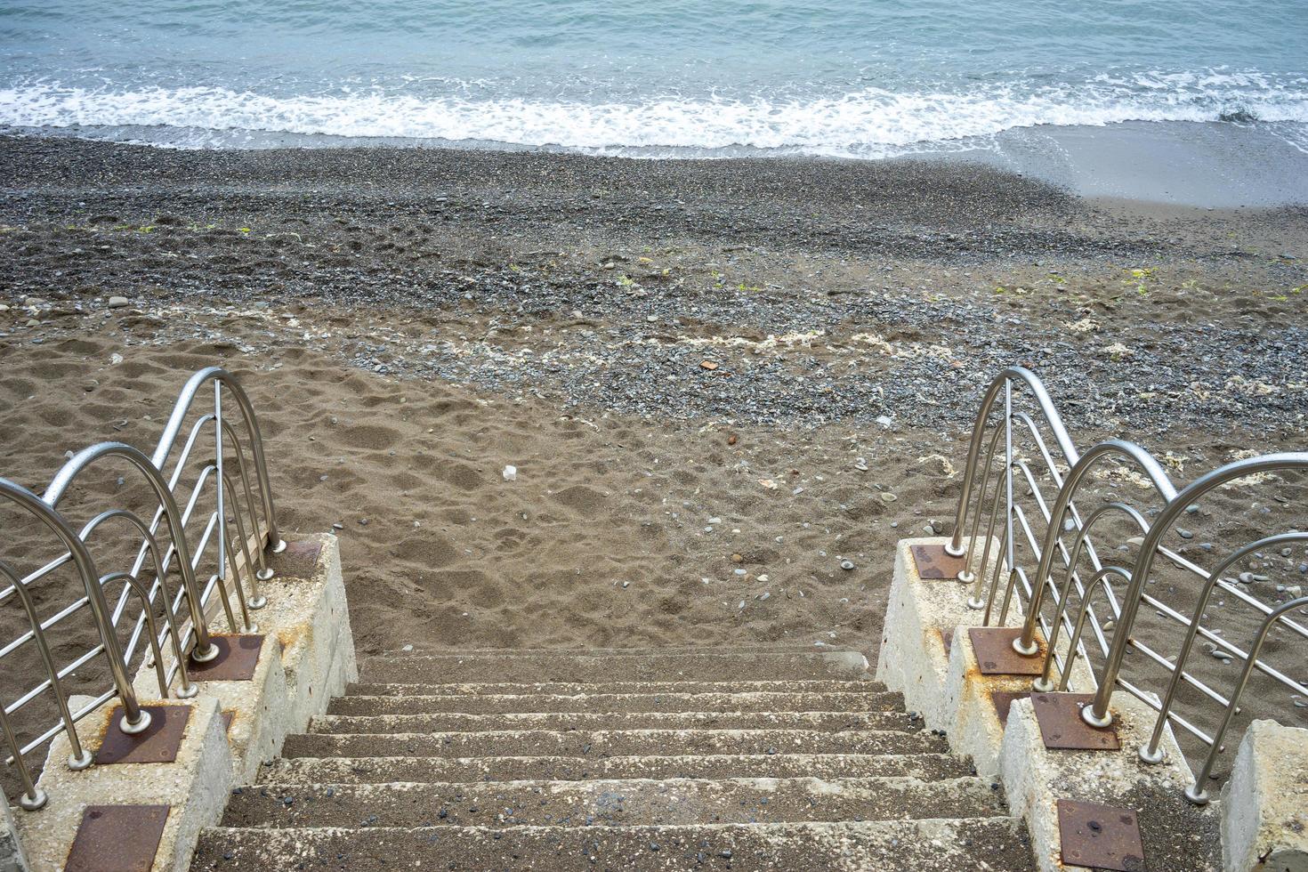 scale di cemento che conducono a una spiaggia e a uno specchio d'acqua foto