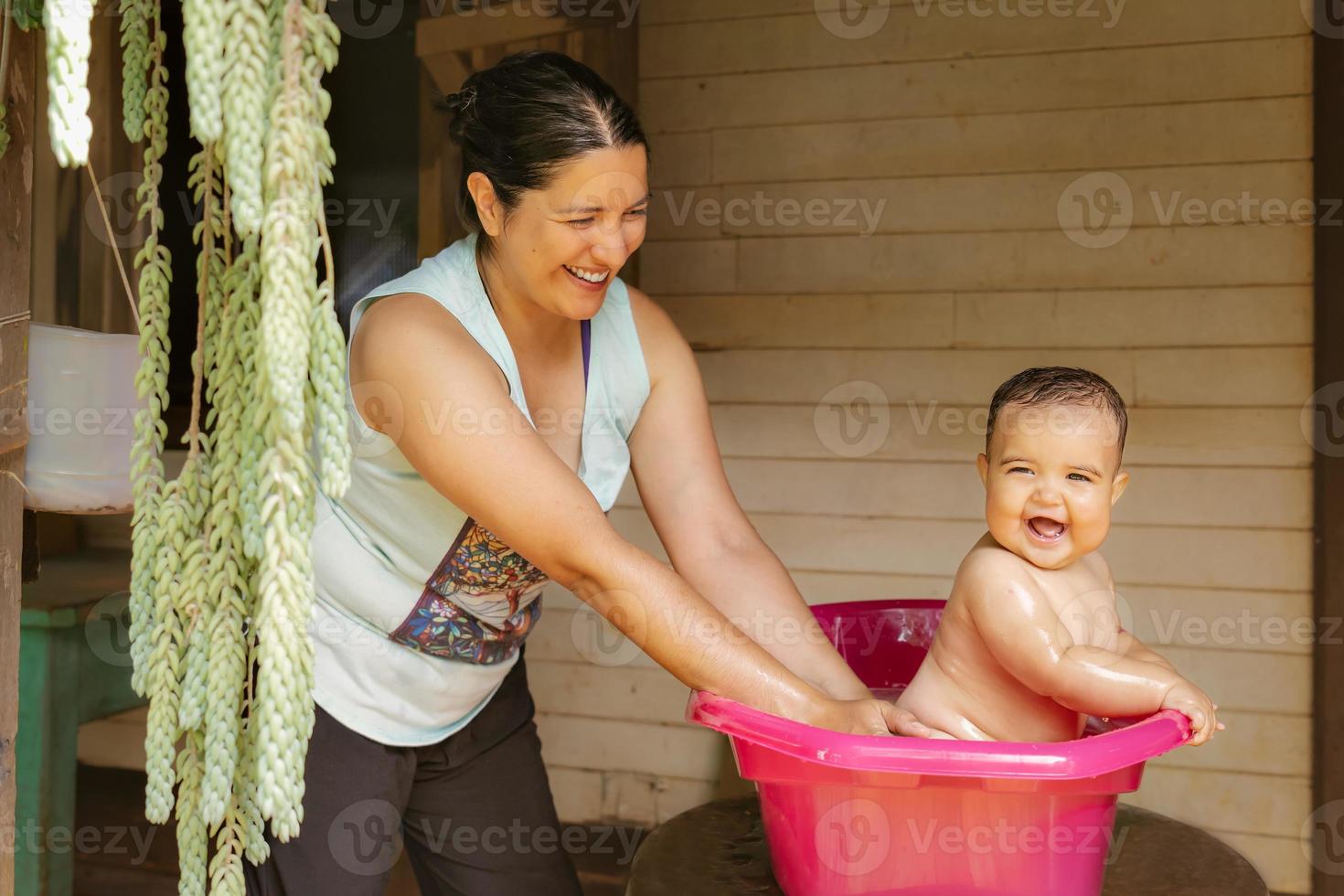 un' bambino bagna con il suo madre nel il giardino. lui ha un' lotto di divertimento e gode il acqua su un' caldo giorno. foto