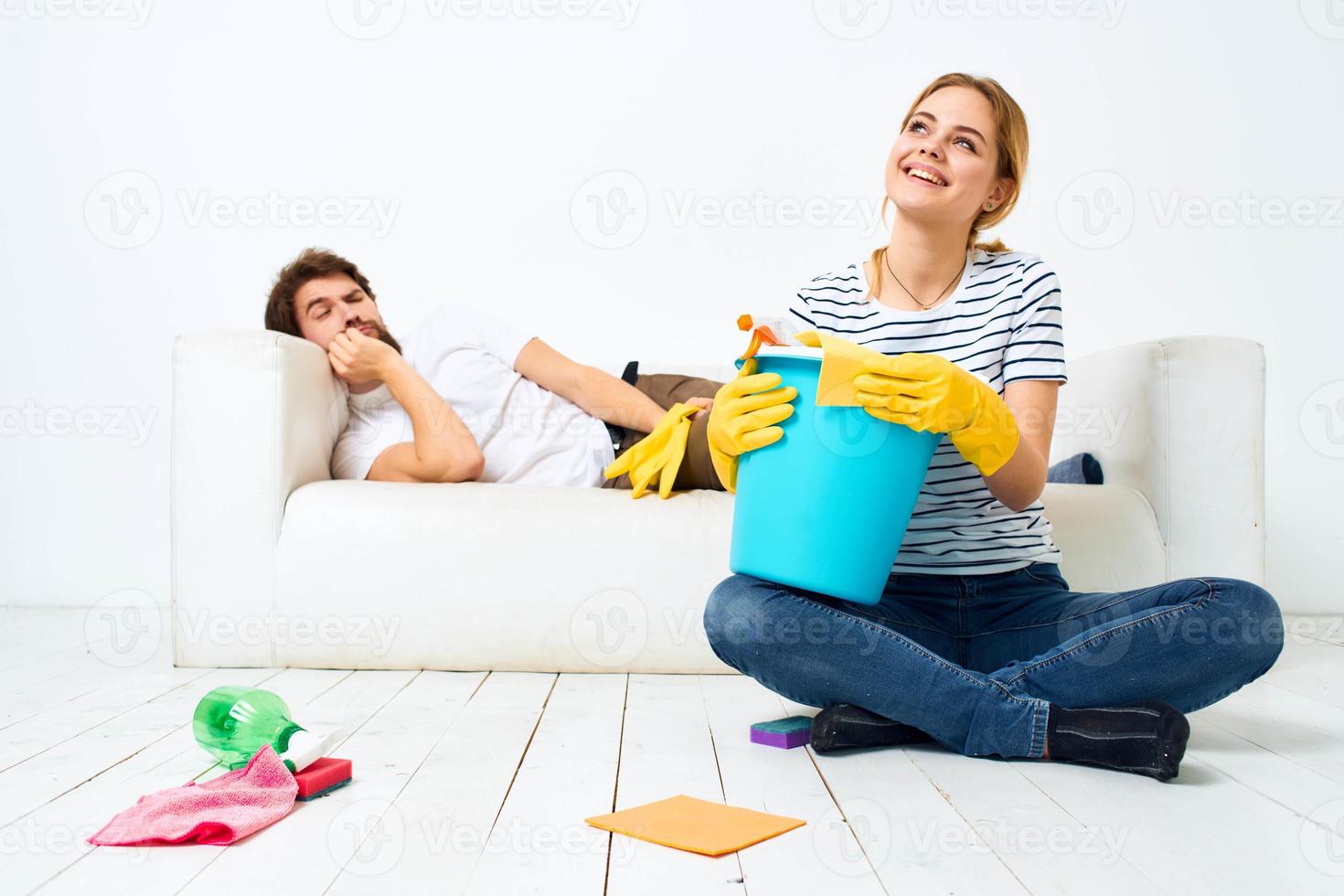 il marito bugie su il divano mentre il suo moglie pulisce su il interno opera foto