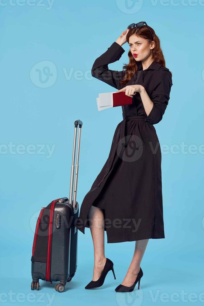 donna nel nero cappotto valigia passaporto e aereo biglietto viaggio foto