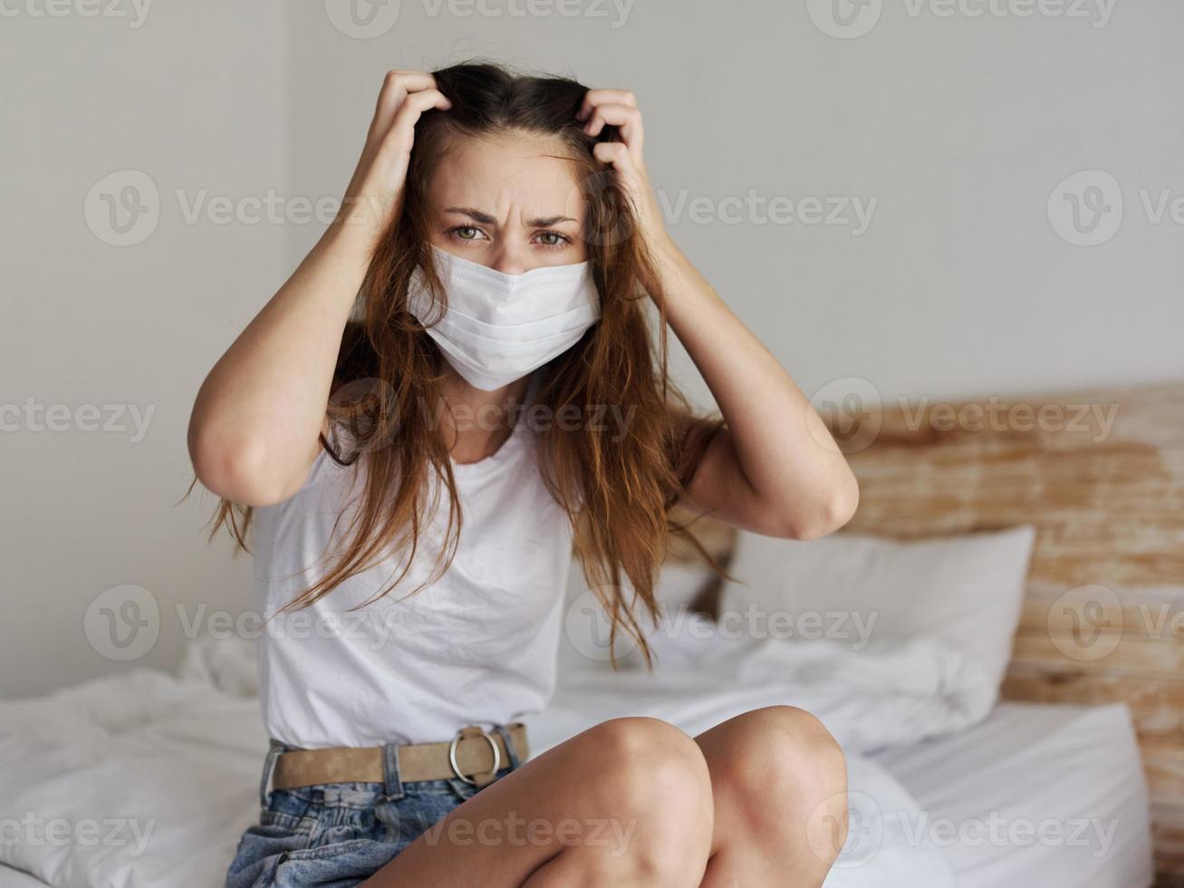 donna nel quarantena tocchi sua testa con sua mani e si siede su il letto viaggio modello coronavirus foto