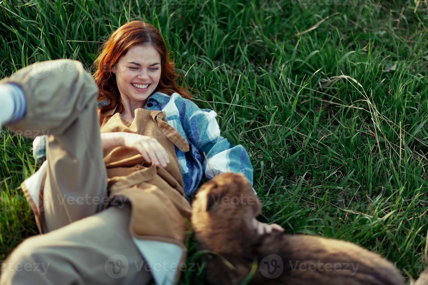 donna dire bugie su il erba sorridente giocando e coccole sua cane nel natura nel il parco nel il estate tramonto. il concetto di Salute e amore di animali, trattamento di zecche e pulci erba e animali foto