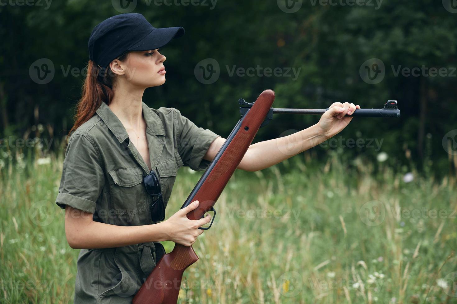 donna su all'aperto nel un' verde tuta da lavoro, ricaricare un' pistola nel il sfondo di natura Armi foto