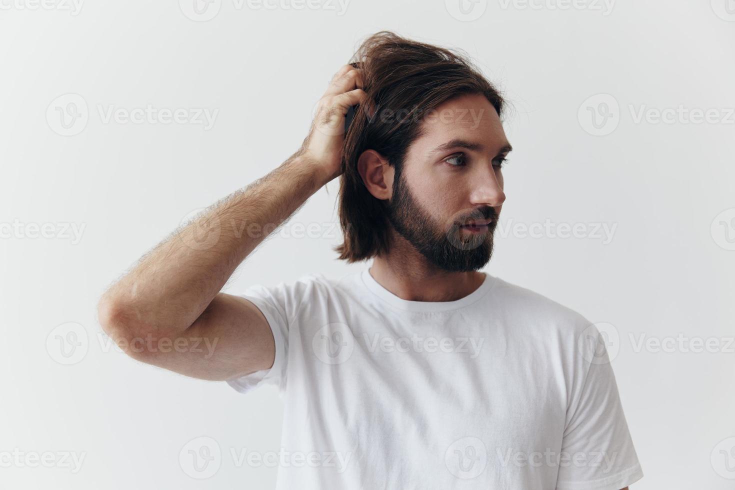 ritratto di un' uomo con un' nero di spessore barba e lungo capelli nel un' bianca maglietta su un' bianca isolato sfondo emozione di tristezza e brama foto