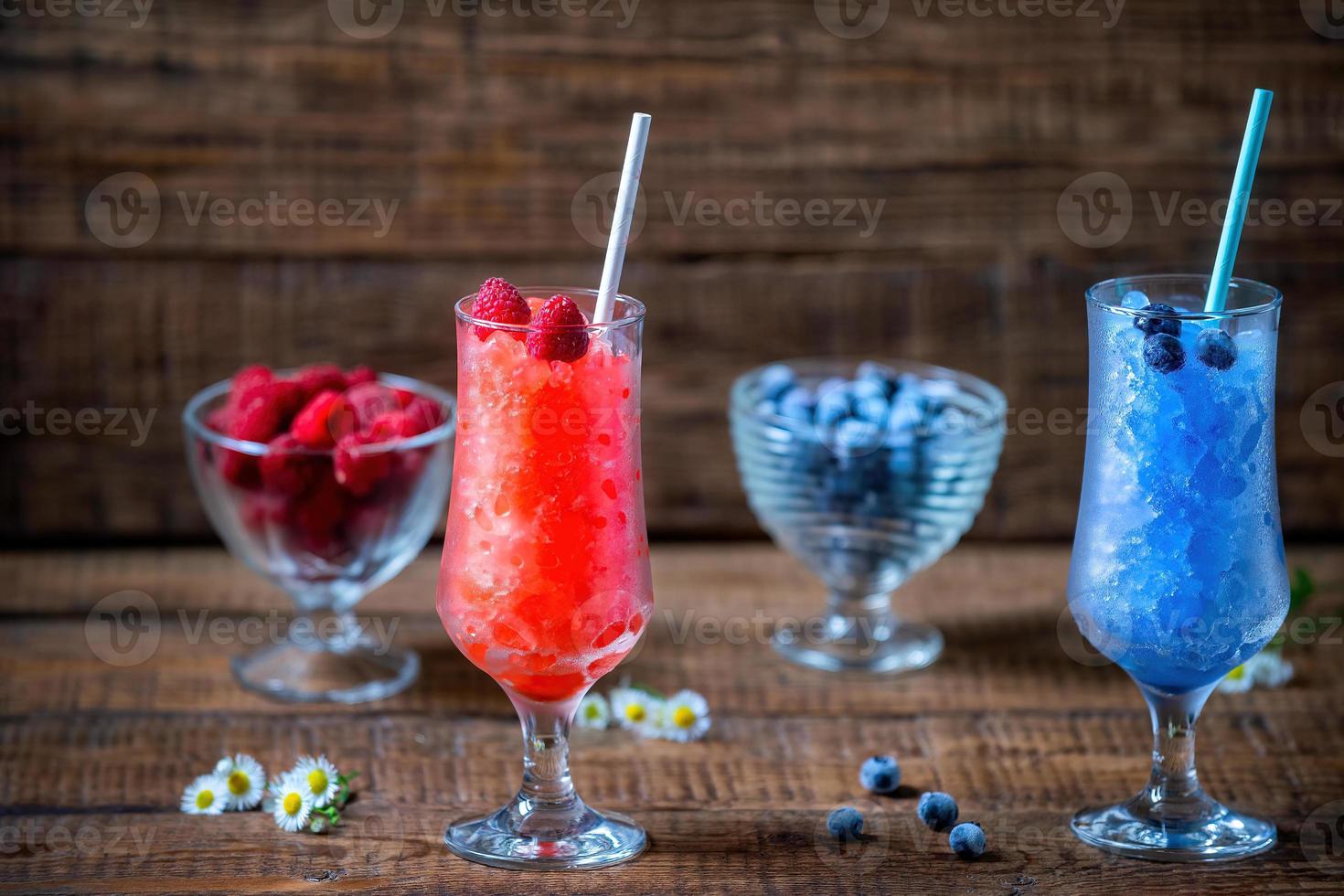 estate siciliano granito dolce, congelato lamponi, mirtillo succo nel grande bicchiere bicchieri su un' di legno sfondo con fresco frutti di bosco. estate freddo, Tonico schiacciato ghiaccio cocktail foto