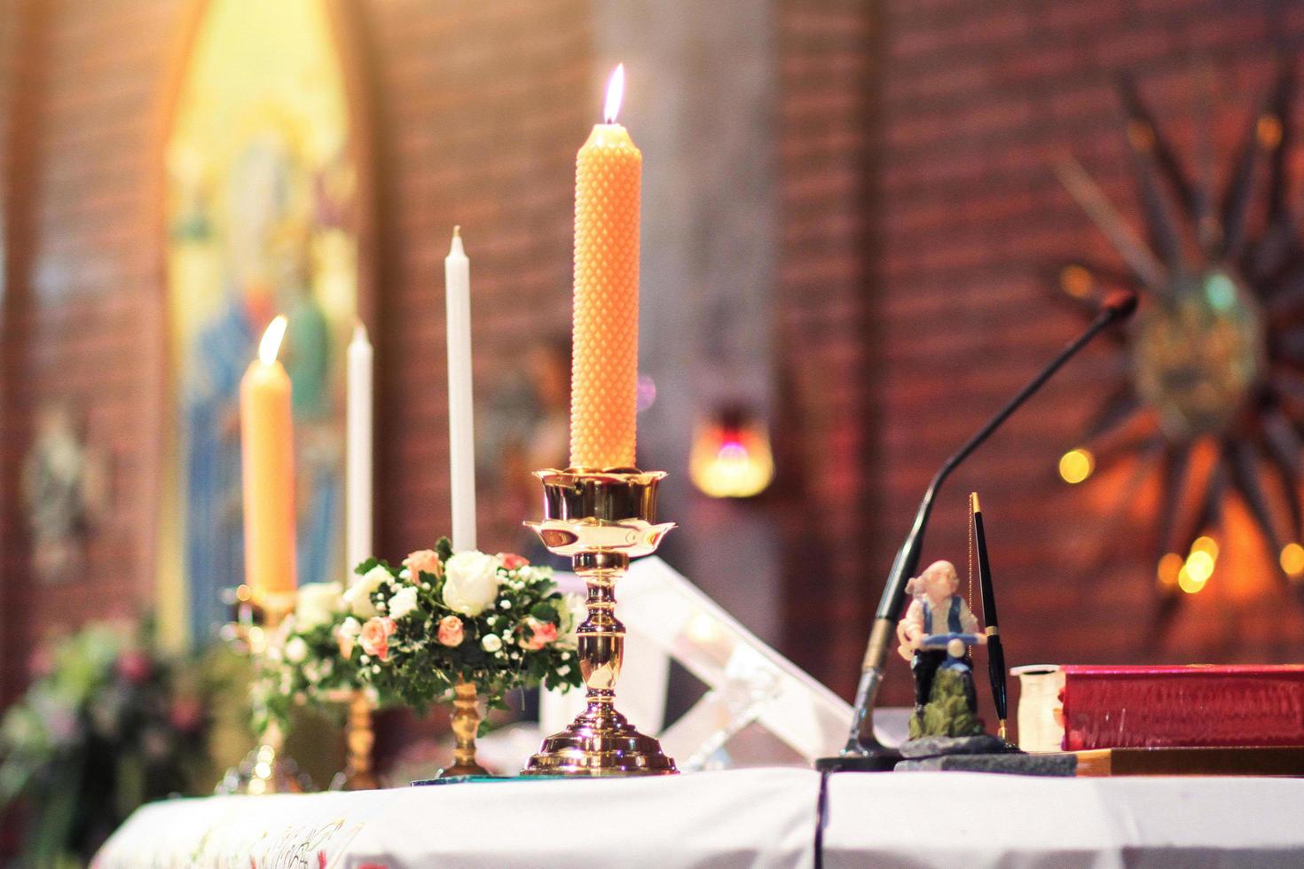 decorazione su il nozze tavolo con candela, rosa vaso, libro, penna nel cristiano matrimonio. nozze cerimonia nel cristiano Chiesa foto
