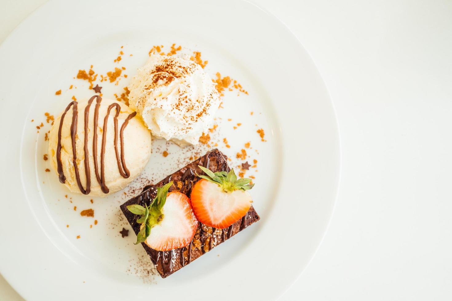 gelato alla vaniglia con torta brownie al cioccolato con fragole in cima foto