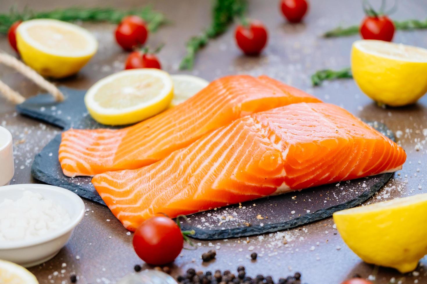 filetto di carne di salmone crudo e fresco su ardesia di pietra nera foto