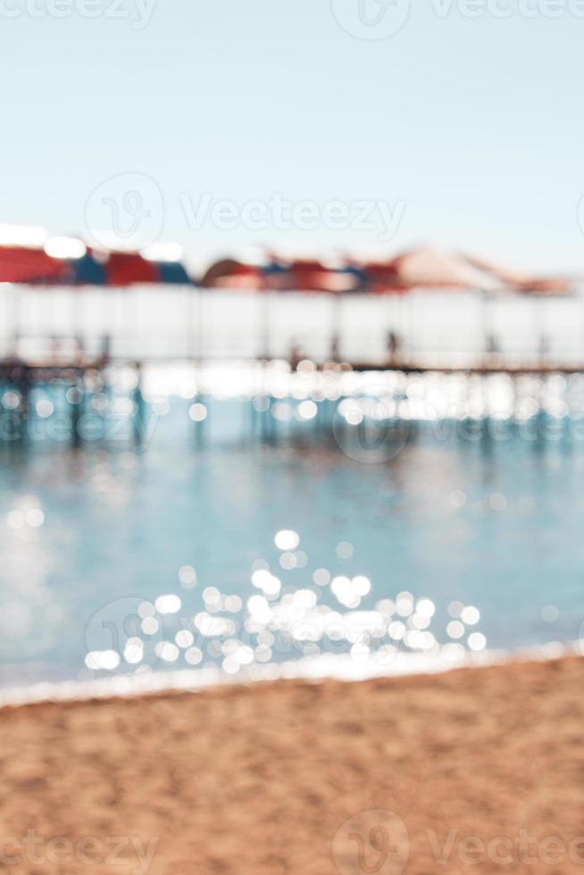 sfocato sfocato spiaggia con molo, parasole, mare con bokeh sfondo. riposo, viaggio. verticale. copia spazio foto