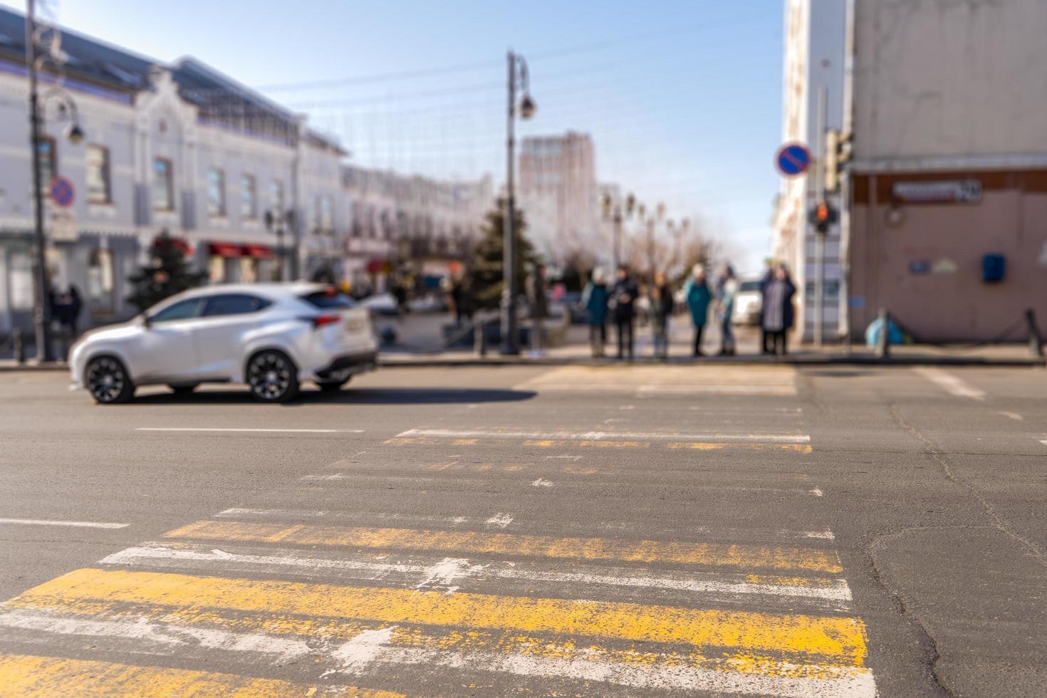 paesaggio urbano di un attraversamento pedonale con persone sfocate, automobili ed edifici a vladivostok, in russia foto