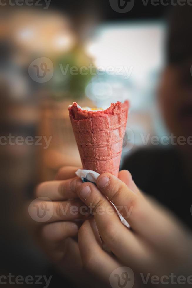 gustoso freddo cremoso vaniglia ghiaccio crema nel un' rosso zucchero cono tenuto nel il tuo mano foto