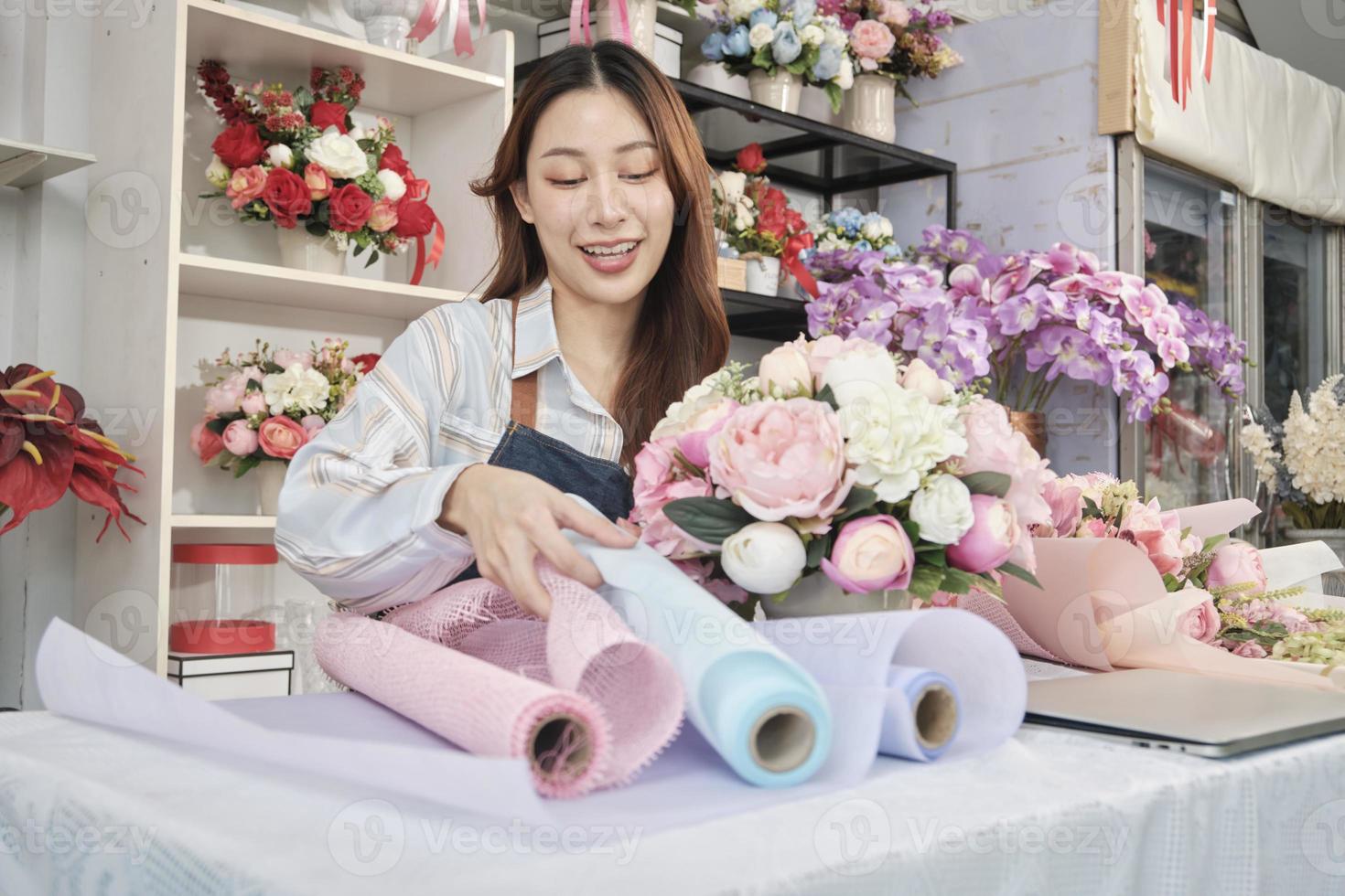 giovane bellissimo asiatico femmina fioraio lavoratore organizzazione mazzo di fiori su bello san valentino, contento opera nel colorato fiore negozio memorizzare con fresco fioritura mazzi di fiori decorare, pmi attività commerciale imprenditore. foto