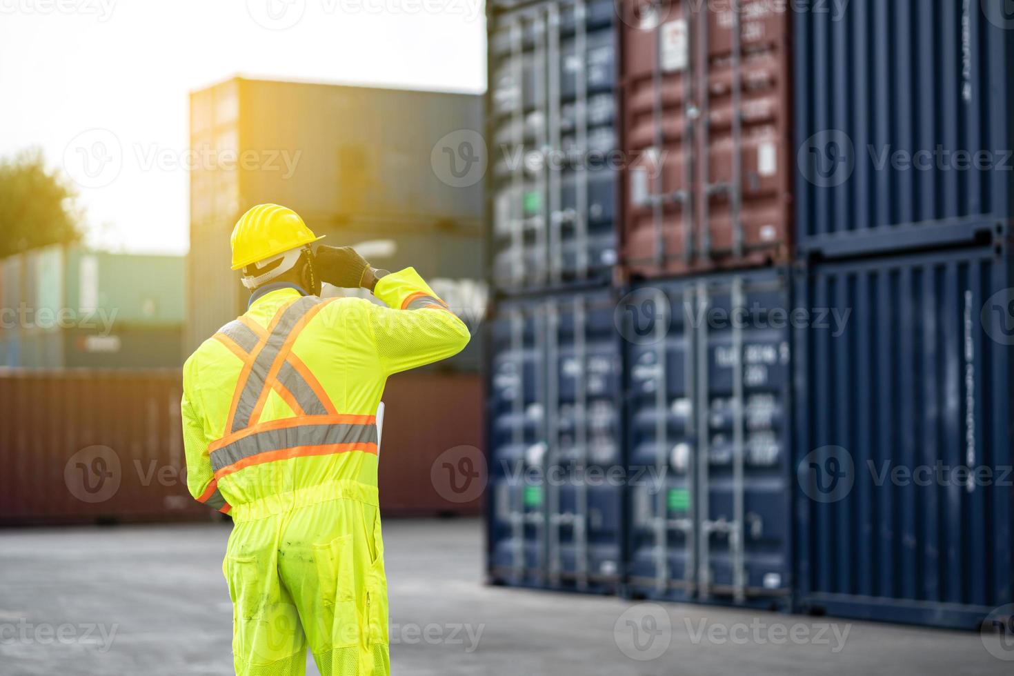 africano tecnico bacino lavoratore nel protettivo sicurezza tuta uniforme e con elmetto protettivo e uso il computer portatile computer a carico contenitore spedizione magazzino. mezzi di trasporto importare, esportare logistica industriale foto