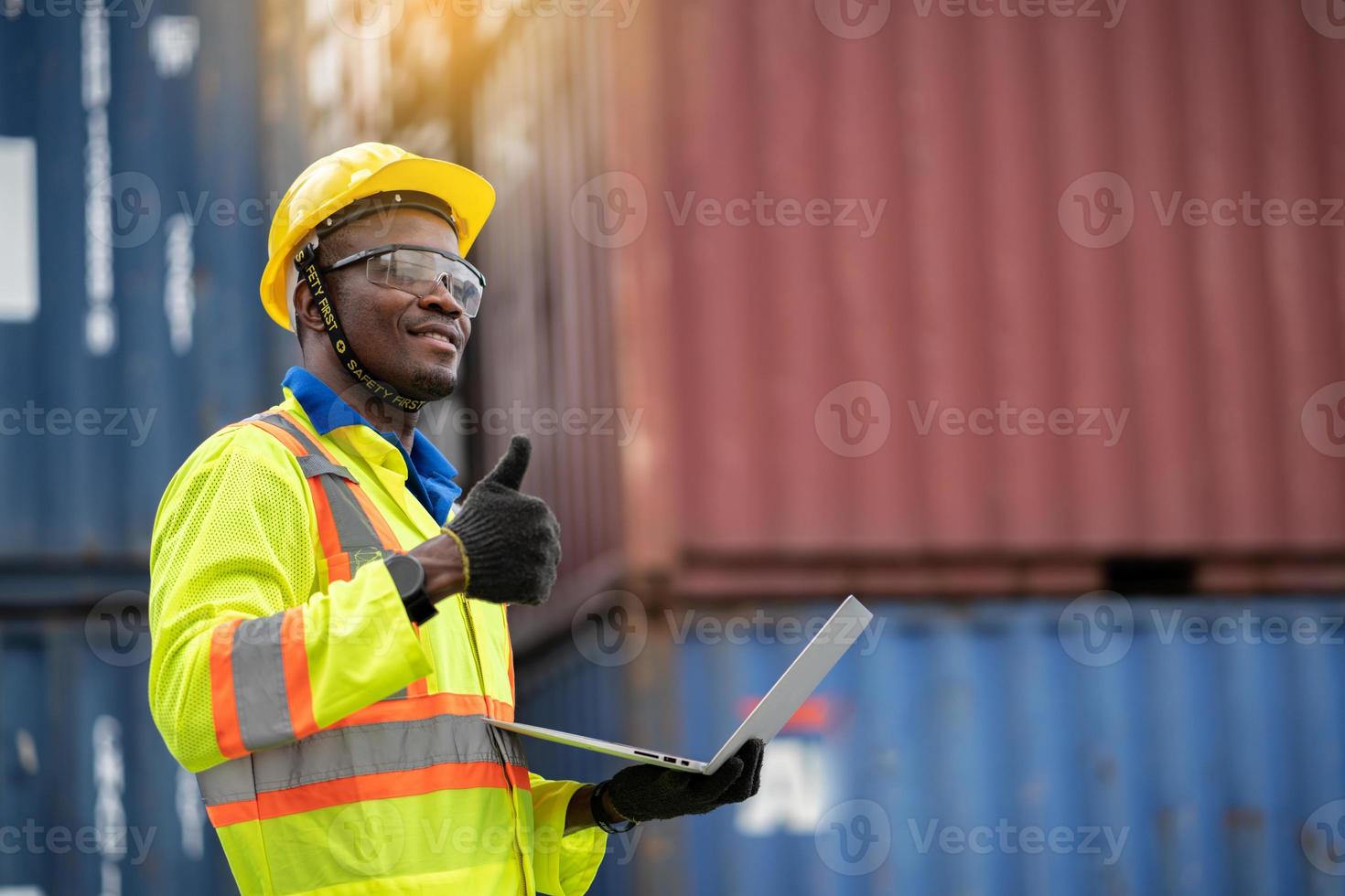 ingegnere uomo lavoratore nel protettivo sicurezza tuta uniforme con giallo elmetto protettivo e uso il computer portatile dai un'occhiata contenitore a carico spedizione magazzino. mezzi di trasporto importare, esportare logistica industriale servic foto