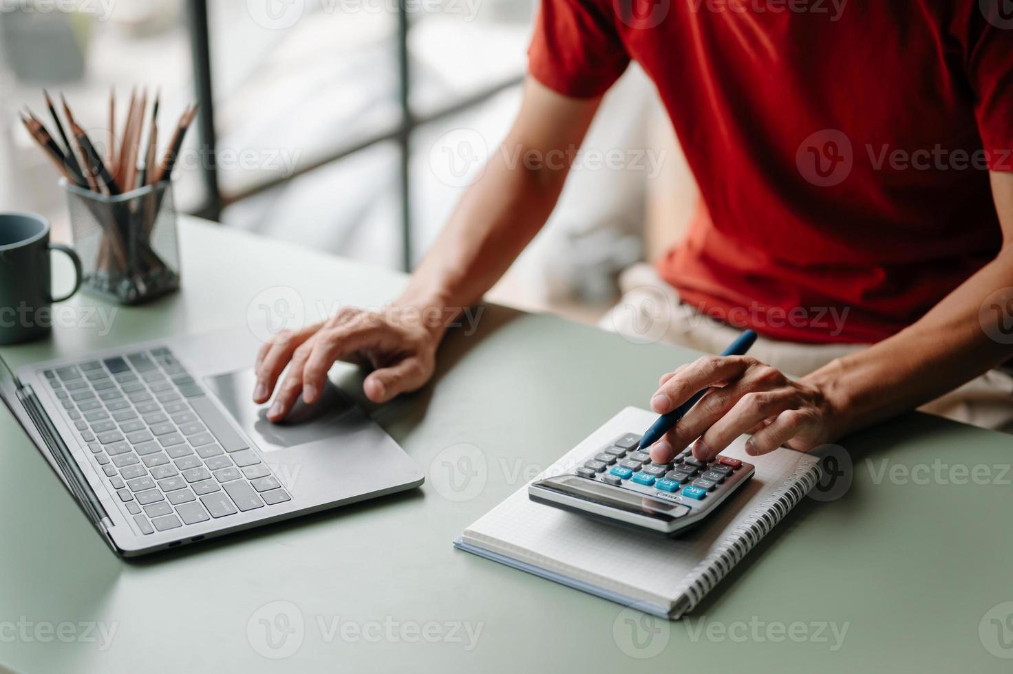 donne che contano monete sulla calcolatrice che prendono dal salvadanaio. mano che tiene la penna che lavora sulla calcolatrice per calcolare sulla scrivania i costi dell'ufficio a casa. foto