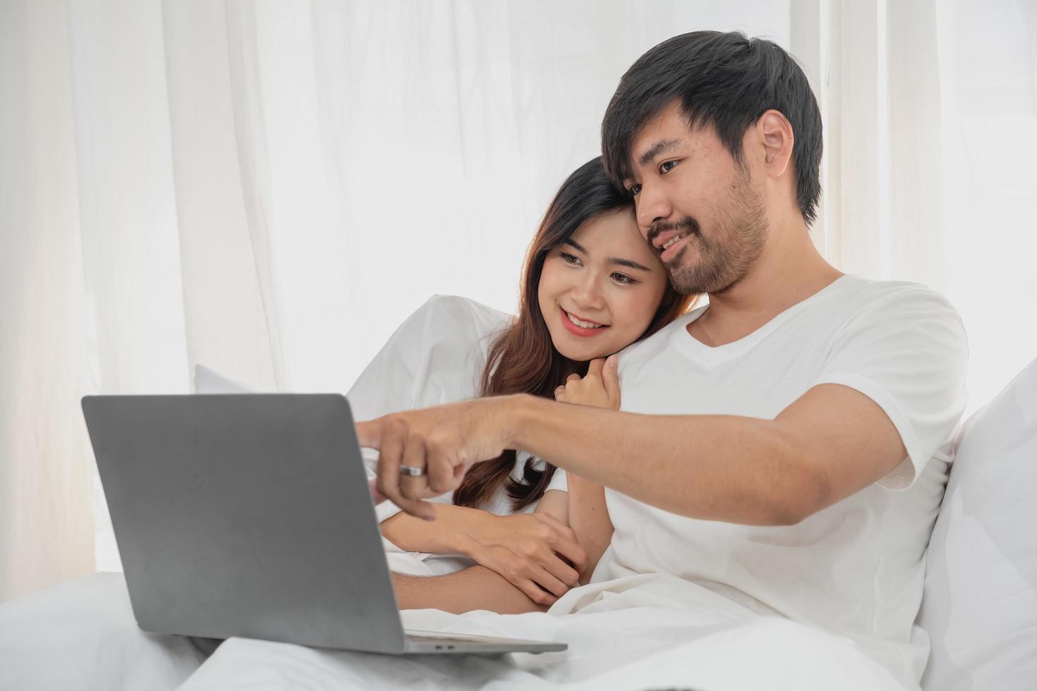 giovane contento asiatico coppia utilizzando il computer portatile nel letto Guardando film, romantico tempo per migliorare famiglia relazione, famiglia concetto. foto