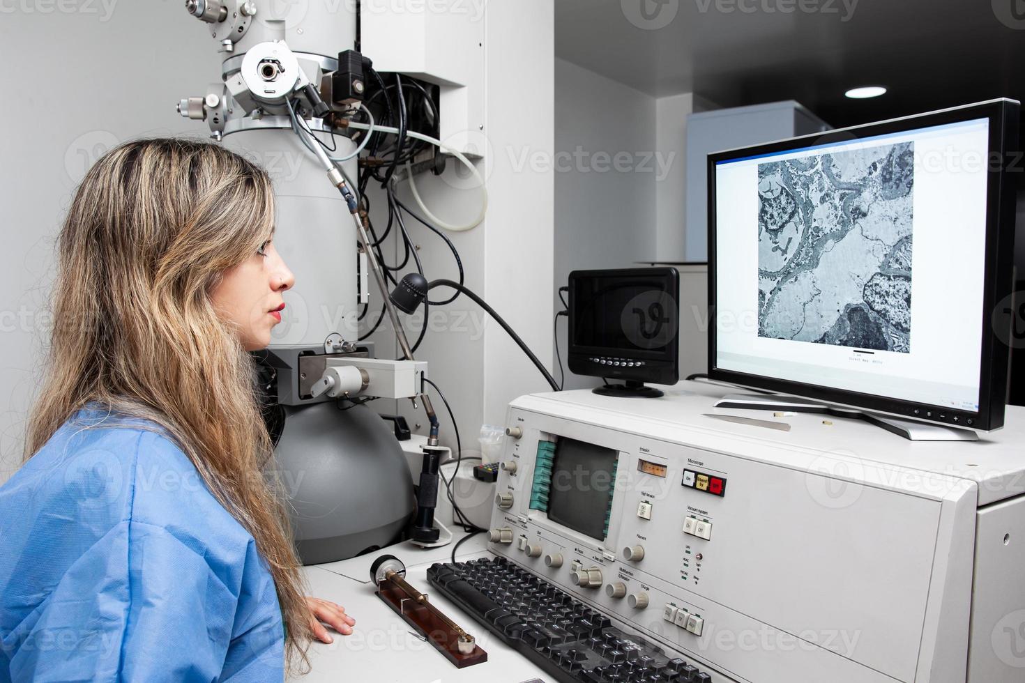giovane femmina scienziato Lavorando a il laboratorio con un elettrone microscopio foto