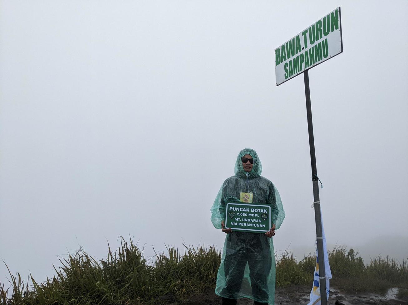 uomo raggiungere picco di montagna quando piovoso giorno con nebbioso vibrazioni. il foto è adatto per uso per avventura soddisfare media, natura manifesto e foresta sfondo.