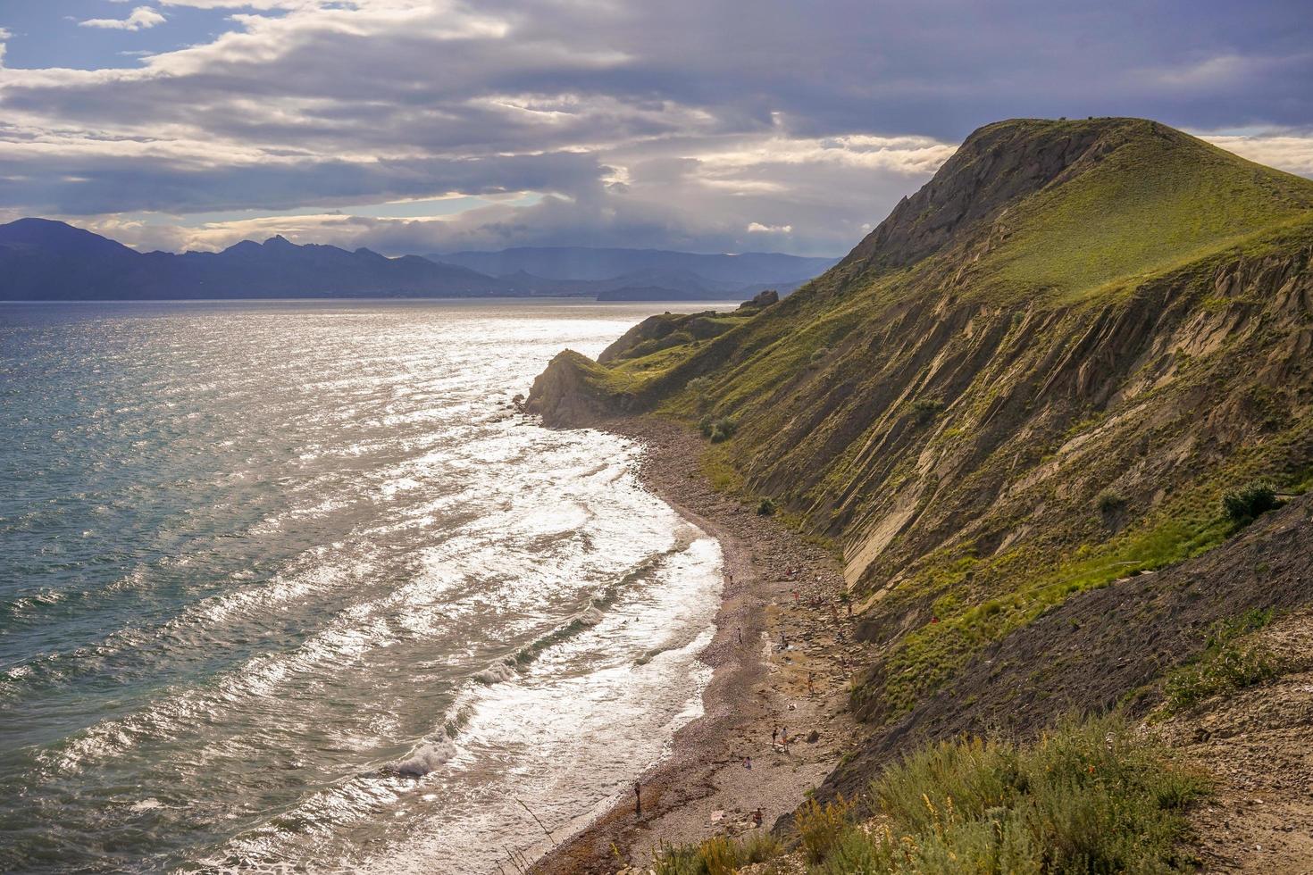 vista sul mare una spiaggia e montagne con un cielo blu nuvoloso vicino a ordzhonikidze, crimea foto