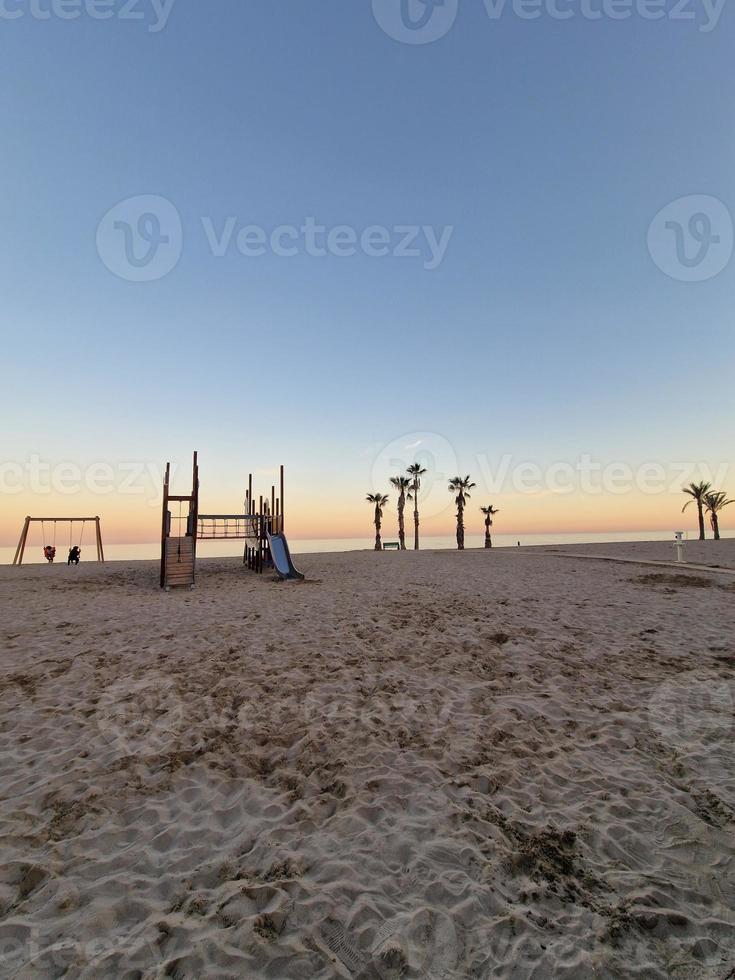 mare paesaggio pace e silenzioso tramonto e quattro palma alberi su il spiaggia e un' panchina foto