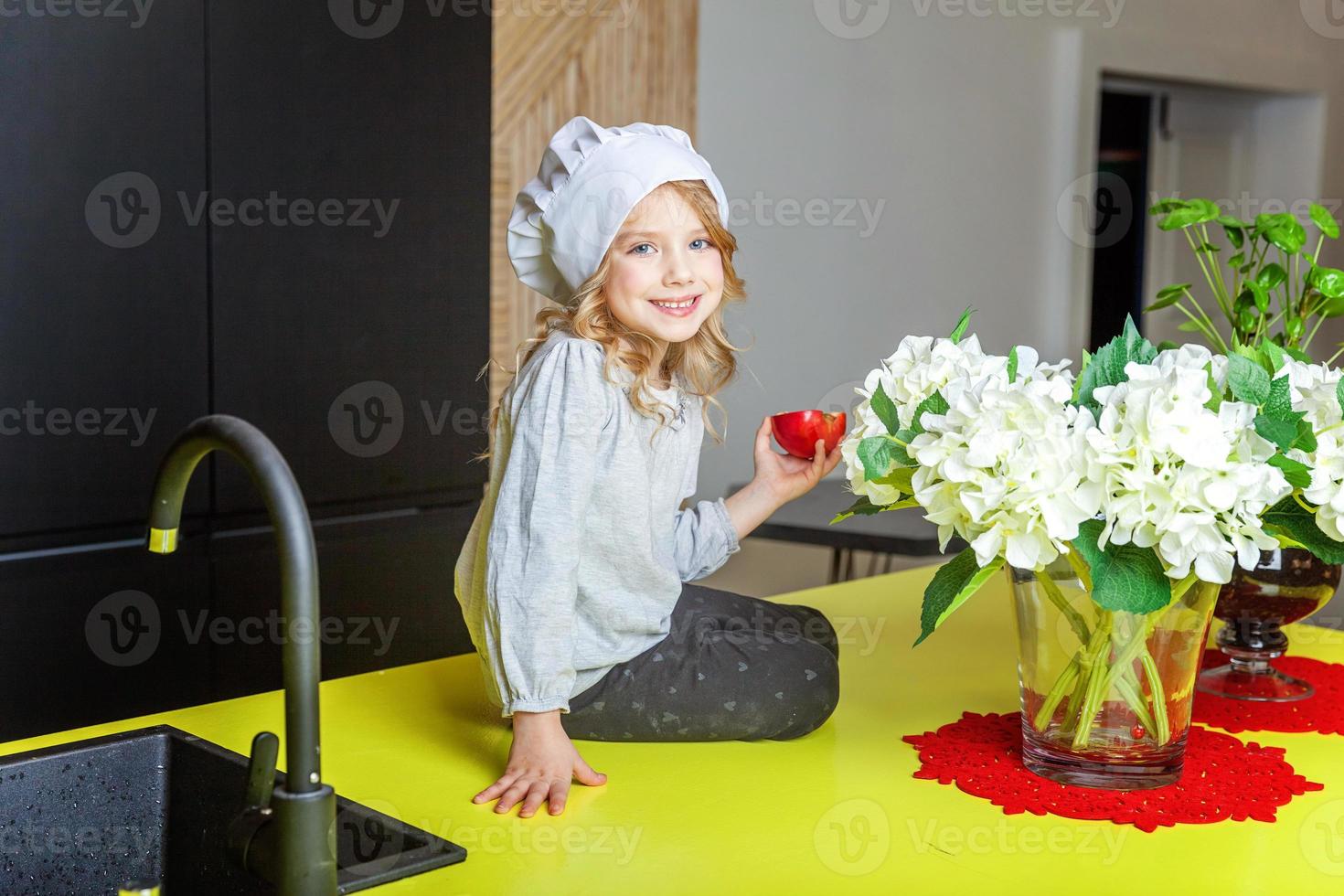 poco ragazza con capocuoco cappello apprendimento cucinando sorridente nel cucina foto