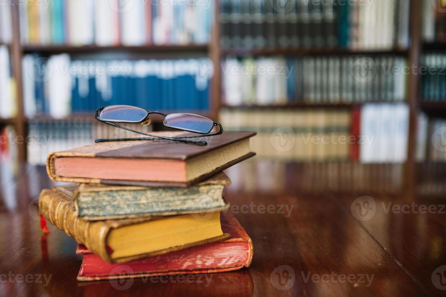 occhiali da vista e vecchi libri sul tavolo della biblioteca foto