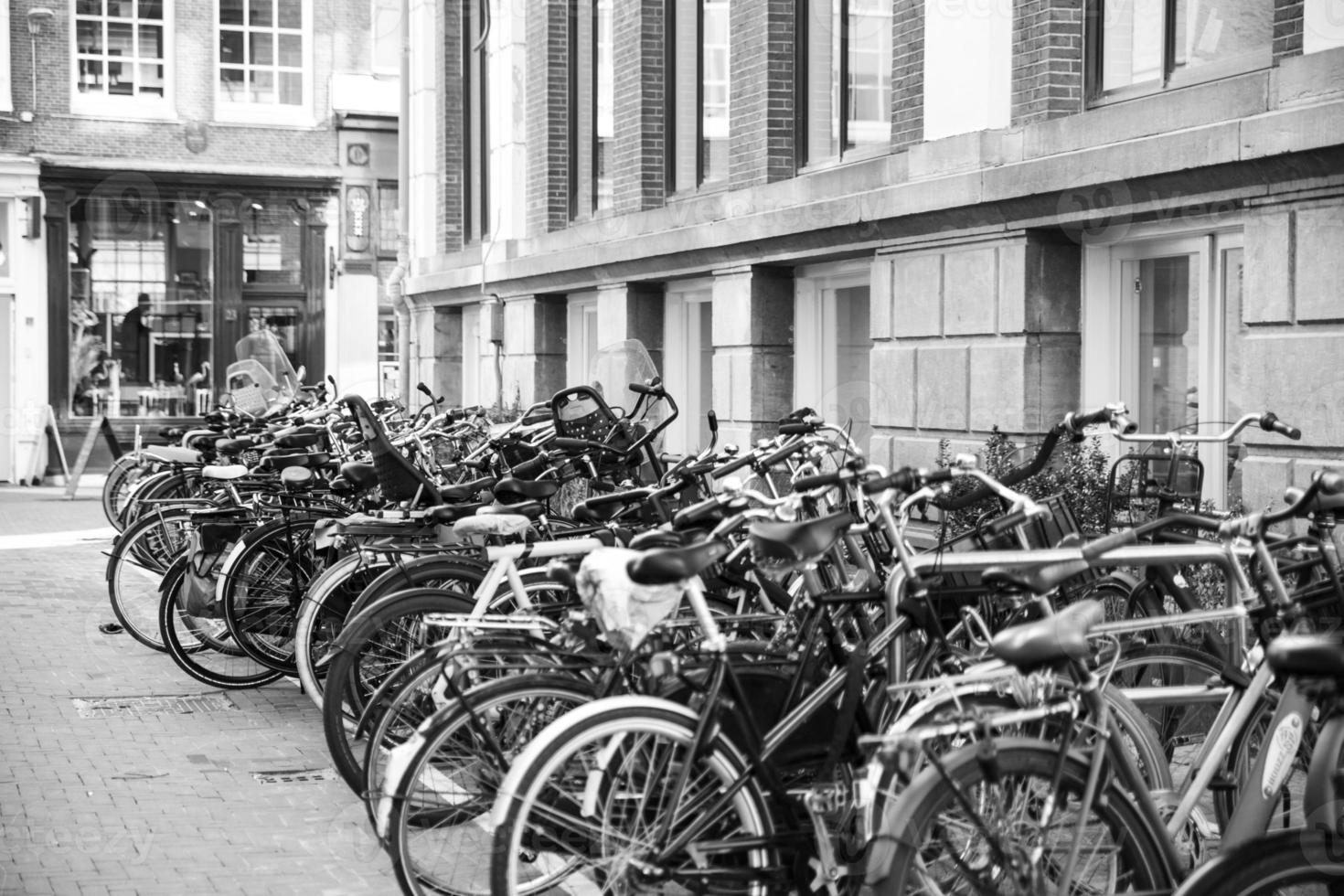 un' bianco e nero fotografia di biciclette parcheggiata nel il centro di amsterdam foto