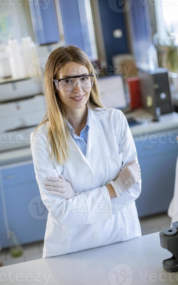 scienziato femminile in camice bianco in piedi nel laboratorio biomedico foto