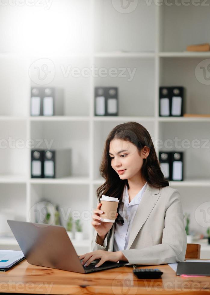 Lavorando donna concetto un' femmina manager frequentando video conferenza e Tenere tavoletta, smatrphone e tazza di caffè foto