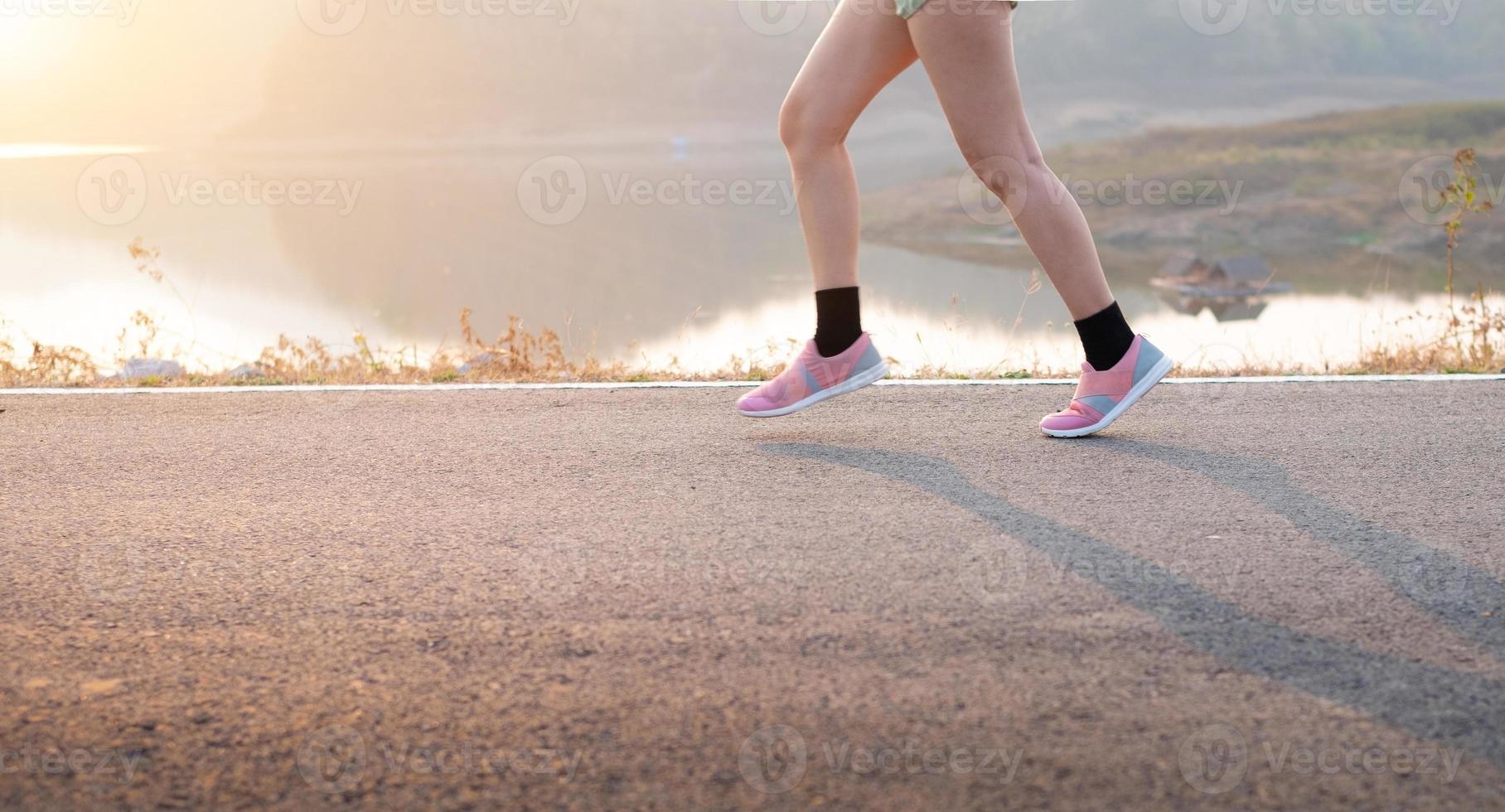 giovane donna che indossa scarpe sportive in esecuzione su strada asfaltata foto