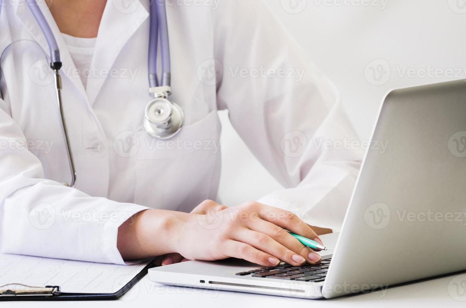 dottoressa con lo stetoscopio al collo utilizzando la scrivania del computer portatile foto